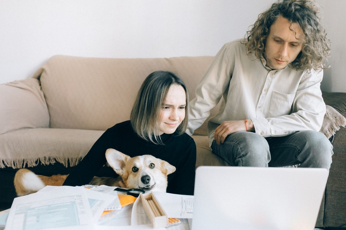 Couple checking documents at home with their dog beside them